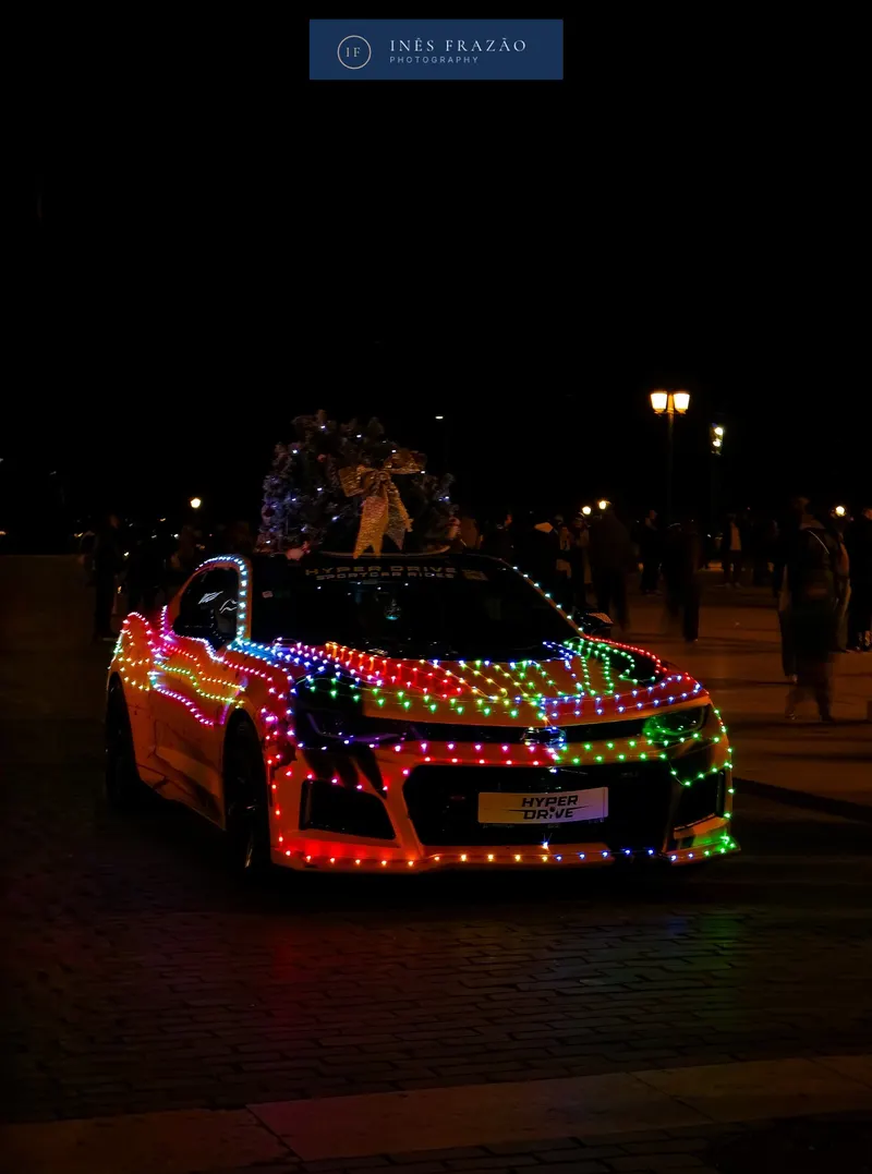 Carro coberto de luzes coloridas a brilhar numa rua escura à noite, fotografia noturna por Inês Frazão.