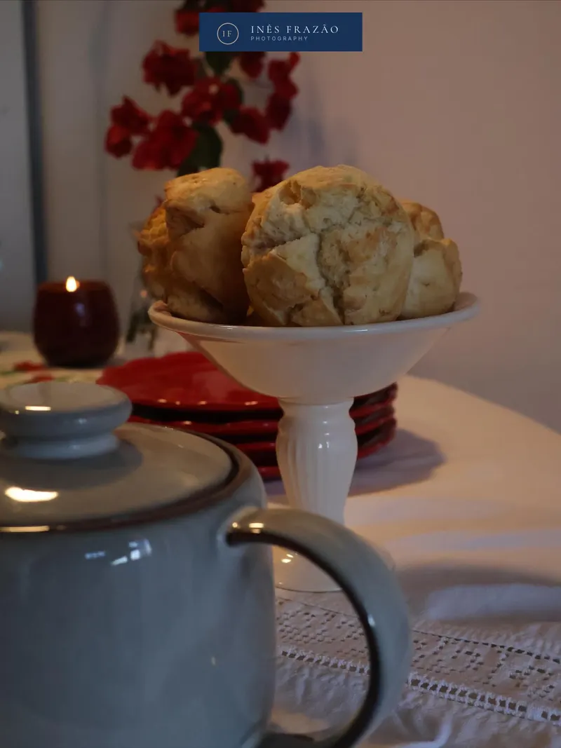 Mesa posta com bolachas, bule e uma vela acesa num ambiente acolhedor, fotografia de lifestyle por Inês Frazão.
