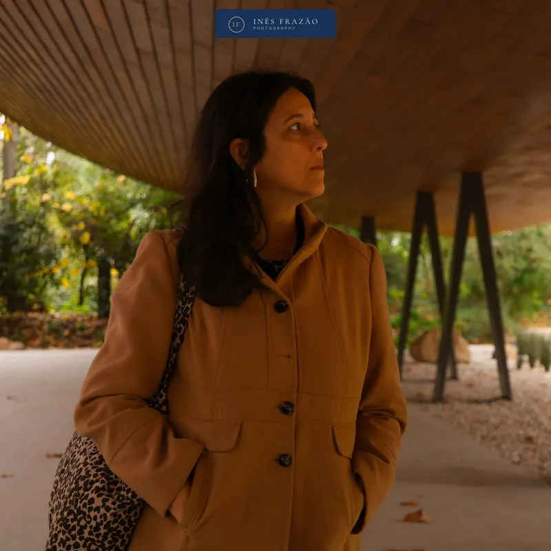 Retrato de uma mulher de casaco castanho a olhar para o lado sob uma cobertura moderna, fotografia de retrato por Inês Frazão.