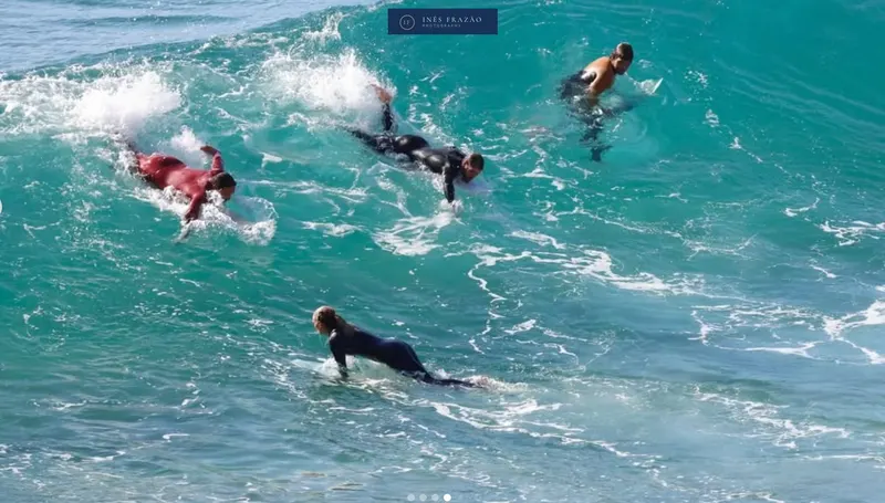 Grupo de surfistas a remar na direção das ondas, numa cena dinâmica que transmite movimento e espírito de equipa. Fotografia de ação por Inês Frazão.