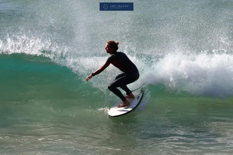 Surfista a deslizar na parede de uma onda entre salpicos de espuma, fotografia de surf por Inês Frazão.