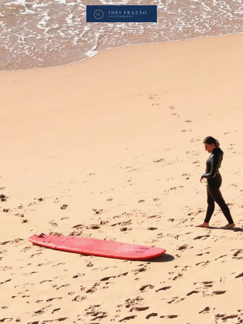 Surfista em pausa na areia, iluminada pela luz natural, num momento tranquilo captado com sensibilidade documental. Fotografia de desporto por Inês Frazão.